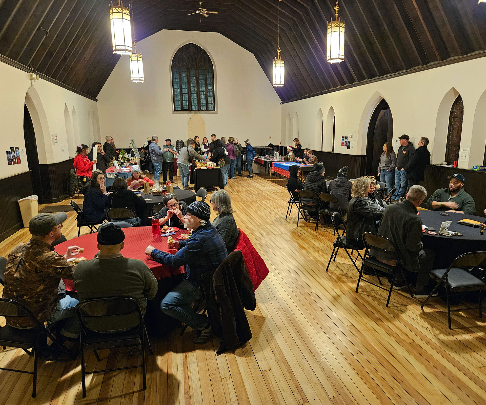 An evening social event with community members seated at tables throughout the hall.